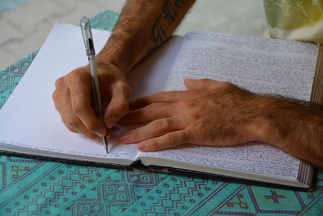 Person writing notes while sitting near a forest trail in Canadian woodland